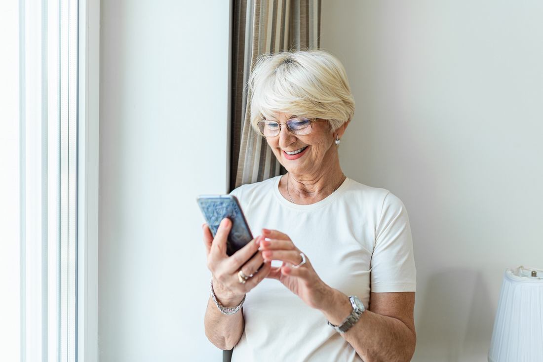 Dexcom G7 Ältere Frau schaut zufrieden auf ihr Smartphone