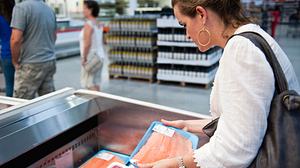 Eine Frau sucht im Supermarkt nach passendem Fleisch. - Foto: iStock / Juanmonino