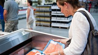 Eine Frau sucht im Supermarkt nach passendem Fleisch. - Foto: iStock / Juanmonino