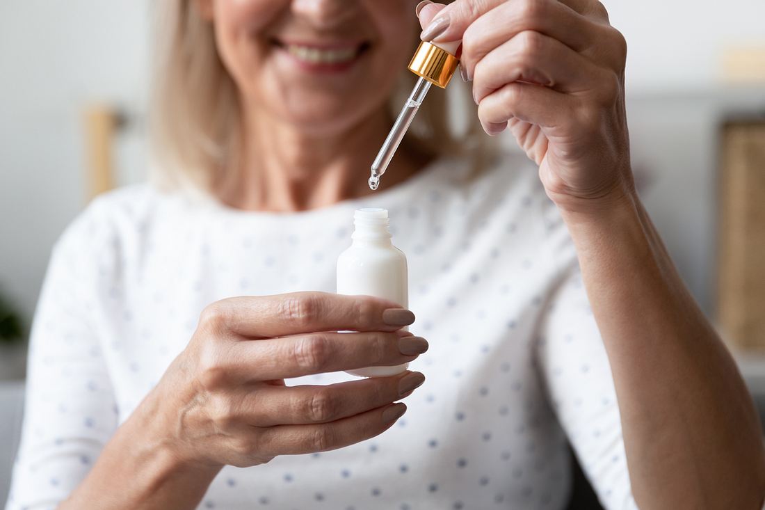 Anti Aging Serum Frau hält Pipette mit Anti Aging Serum hoch