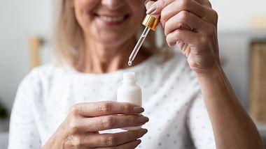 Frau hält Pipette mit Anti Aging Serum hoch - Foto: iStock/ fizkes