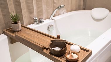 Badewannenablage aus Holz auf gefüllter Badewanne - Foto: iStock/Panupong Piewkleng