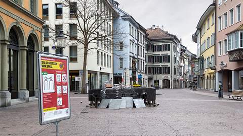 In einer leeren Einkaufsstraße steht ein Schild mit Corona-Schutzmaßnahmen.  - Foto: yuelan / iStock