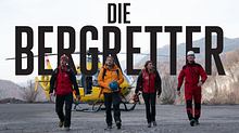Die Bergretter-Hauptdarsteller laufen über einen Schotterplatz, hinter ihnen schwebt das Logo - Foto: ZDF / Martin Zwanzger / Stephanie Kulbach (Bearbeitung und Montage: Liebenswert)