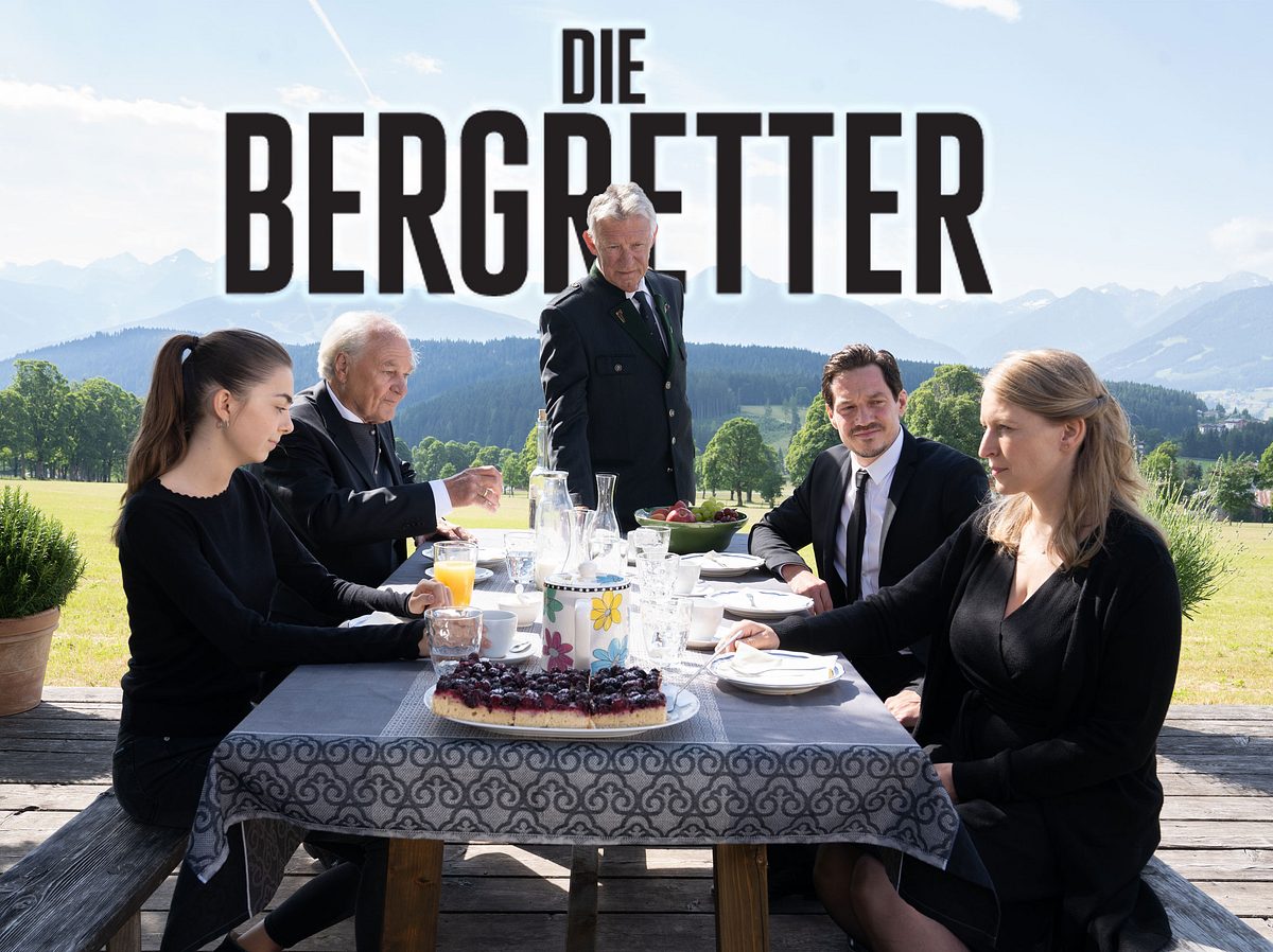 Auf einer Terrasse mit Blick in die Berge sitzen Mia (Mia-Sophie Ballauf), Peter Herbrechter (Michael König), Franz Marthaler (Heinz Marecek), Tobias Herbrechter (Markus Brandl) und Emilie (Stefanie von Poser) um einen gedeckten Kaffeetisch herum.