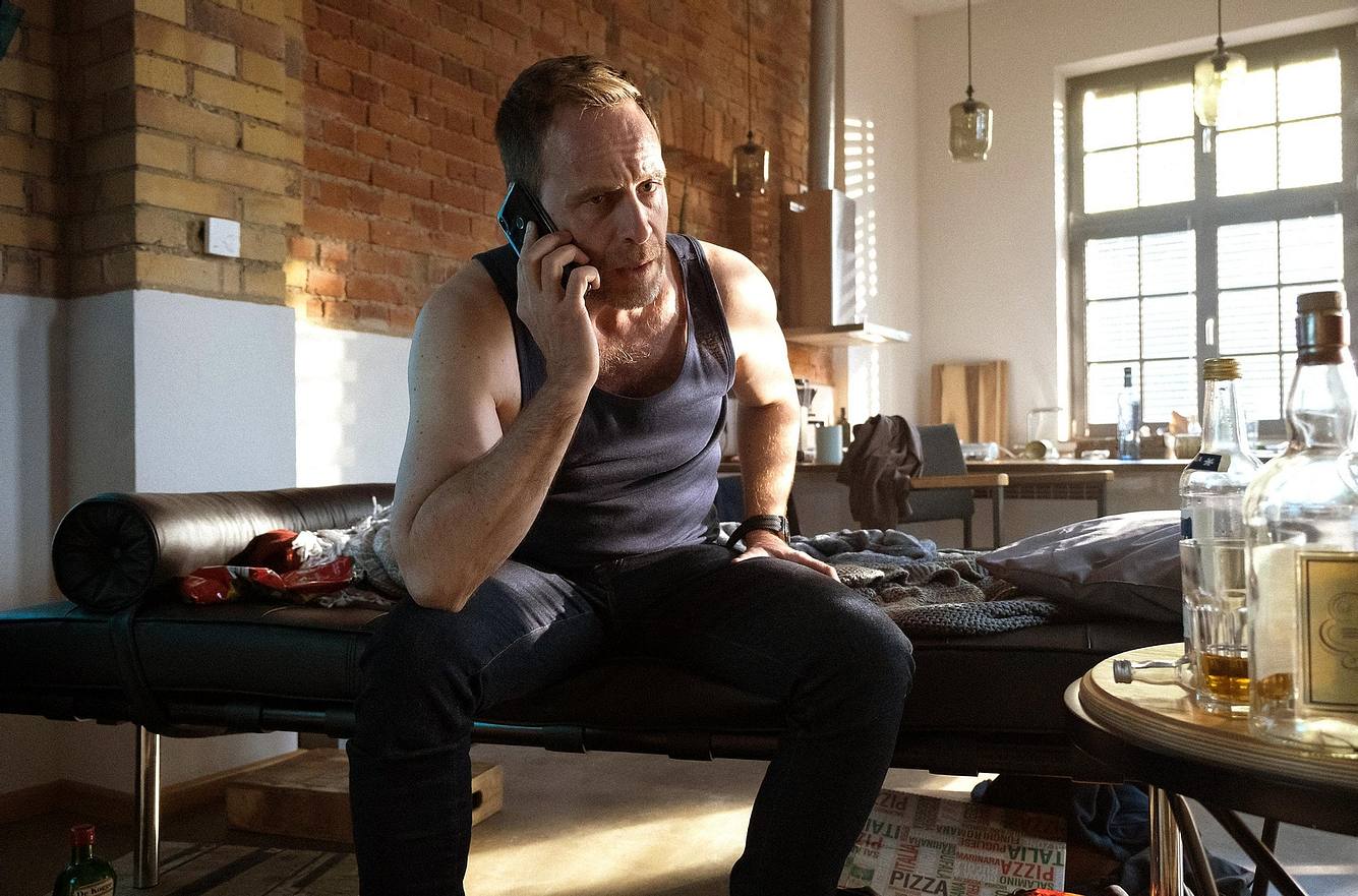 Der Weggang von Maria macht Kai schwer zu schaffen - er fällt in ein tiefes Loch. Dr. Kai Hoffmann (gespielt von Julian Weigend) aus 'In aller Freundschaft' telefonierend auf seiner Couch.