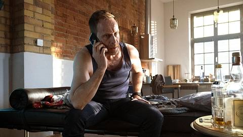 Dr. Kai Hoffmann (gespielt von Julian Weigend) aus In aller Freundschaft telefonierend auf seiner Couch. - Foto: MDR/Saxonia Media/Sebastian Kiss