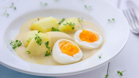 Ein Teller mit Eiern in Senfsoße und Salzkartoffeln.