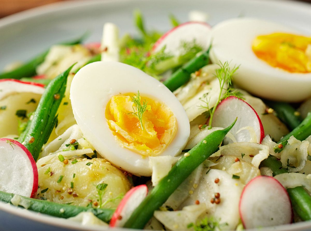Gekochte Eier mit gekochten Kartoffeln, dekoriert mit grünen Bohnen und Radieschen. 