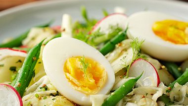 Gekochte Eier mit gekochten Kartoffeln, dekoriert mit grünen Bohnen und Radieschen.  - Foto: haoliang / iStock