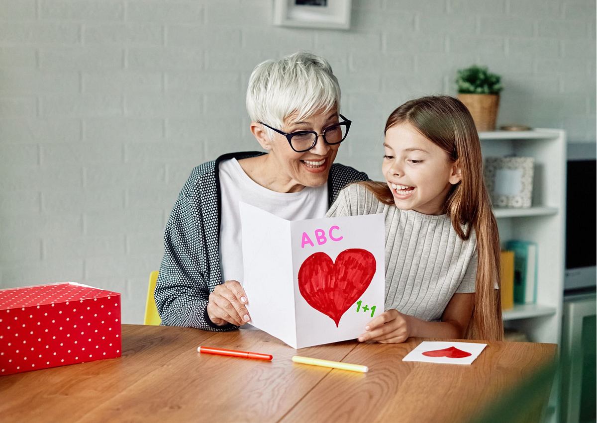 Oma liest ihrer Enkelin die Einschulungskarte vor