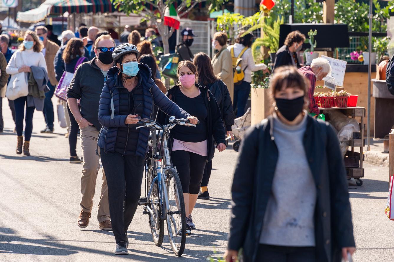 Für viele Bürger*innen ist eine Maskenpflicht unter freiem Himmel bei niedrigen Corona-Zahlen nicht mehr nachvollziehbar. Menschen tragen in einer Fußgängerzone einen Mund-Nasen-Schutz.