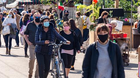 Menschen tragen in einer Fußgängerzone einen Mund-Nasen-Schutz. - Foto: iStock / Marc Bruxelle