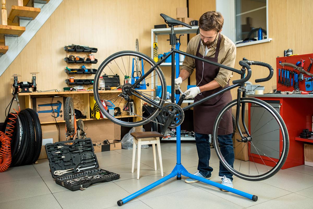 Mann repariert Fahhrad auf einem Fahrrad-Montageständer.