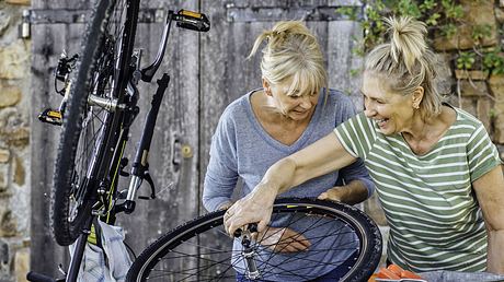 Zwei Frauen reparieren ein Rad.  - Foto: SolStock / iStock