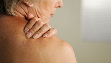 Frau greift sich an schmerzende Schulter.  - Foto: peepo / iStock