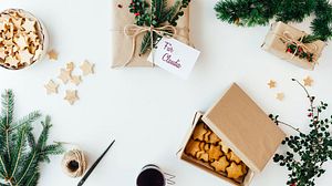 Tisch von oben fotografiert auf dem ein Geschenk, zwei Dose mit Keksen und Kaffeetasse zu sehen ist