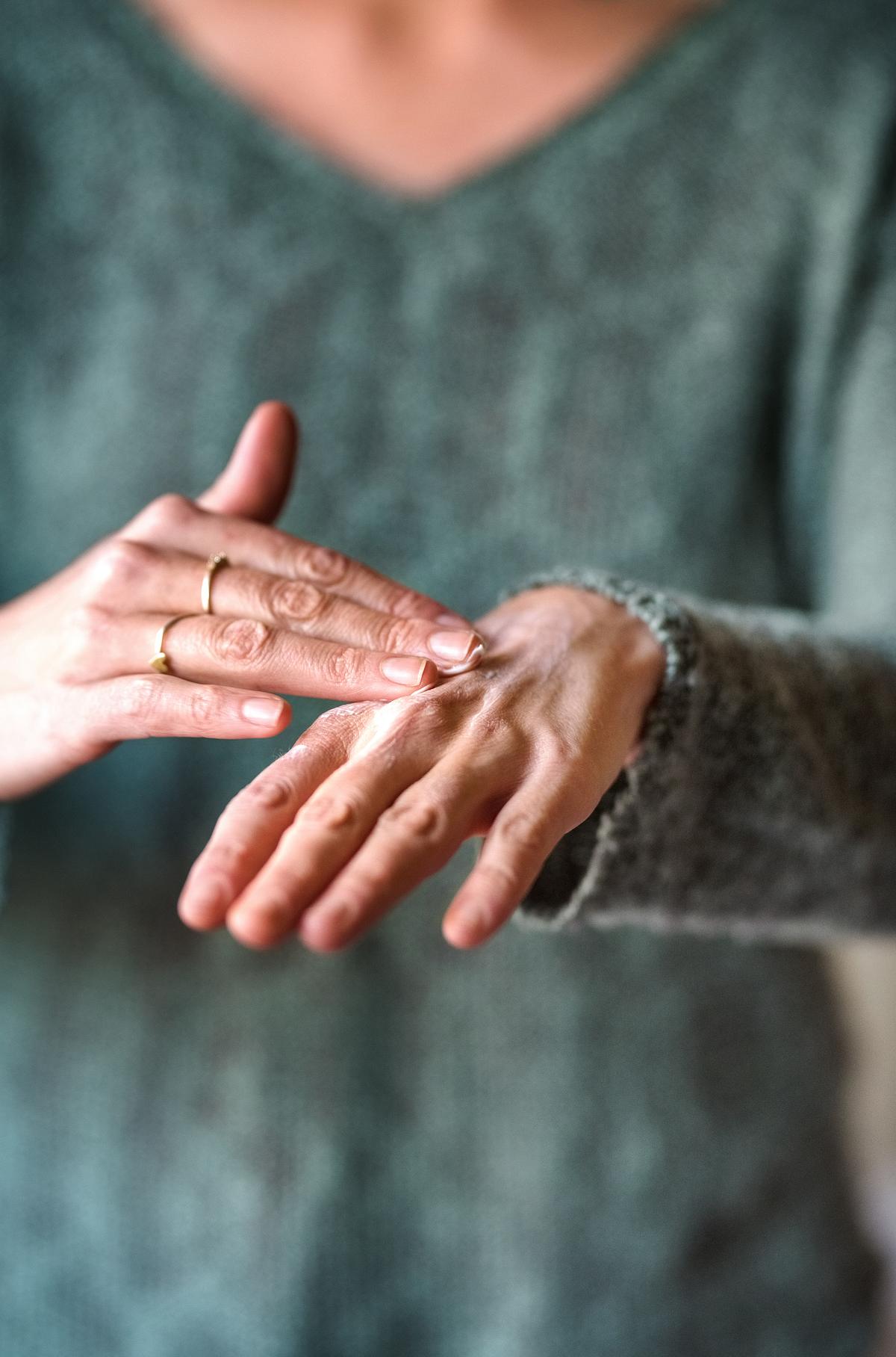 Frau verwendet selbstgemachte Handcreme zum Eincremen.