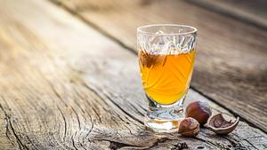 Ein Schnapsglas mit Haselnusslikör, darum ein paar Haselnüsse drapiert. - Foto: Shaiith / iStock