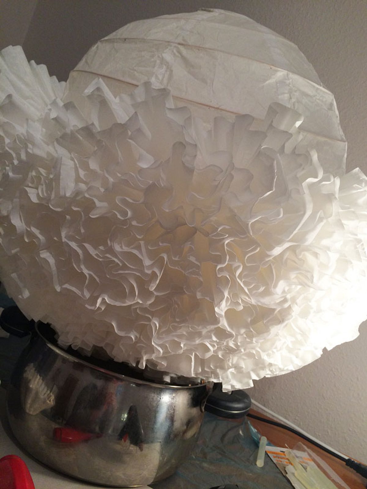 IKEA Lampenschirm mit Kaffeefiltern ist zur Hälfte fertig beklebt.