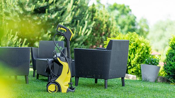 Ein Kärcher Hochdruckreiniger steht im Garten, dahinter eine Sitzecke - Foto: iStock/domin_domin