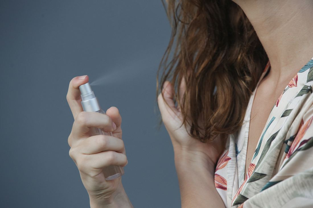 Frau behandelt krauses Haar mit Pflegespray Frau behandelt krauses Haar mit Pflegespray