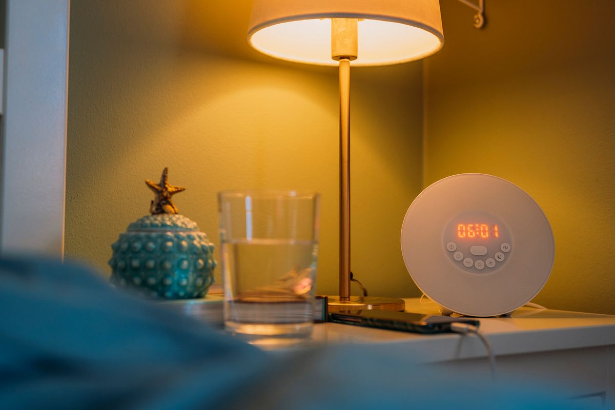 Ein Lichtwecker steht in einem Schlafzimmer auf dem Nachttisch.