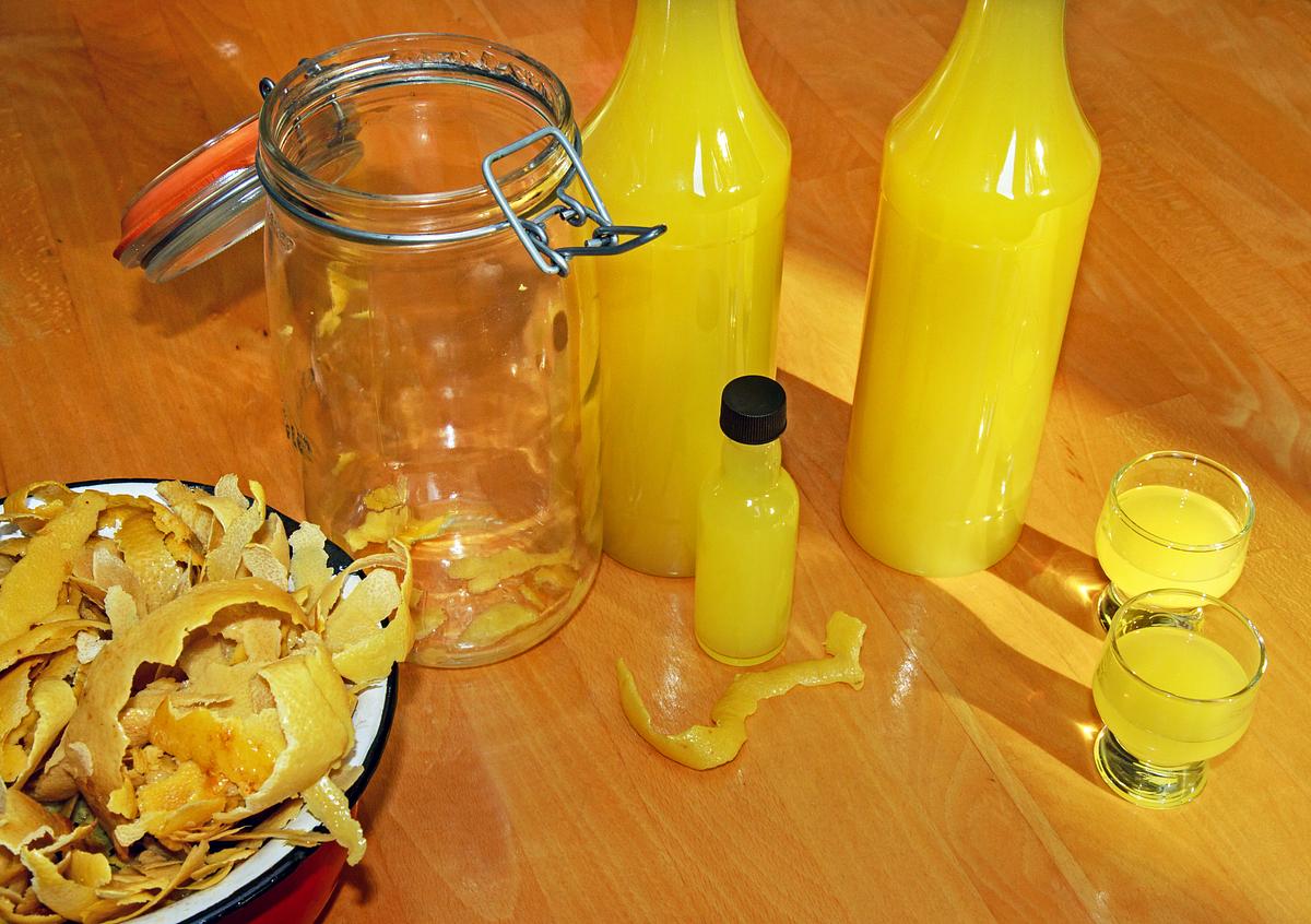 Selbstgemachter Limoncello aus Zitronenschalen auf einem Tisch. 