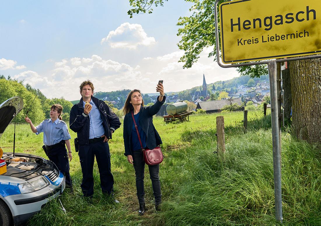 Marie Gabler (Katharina Wackernagel), Heino Fuß (Sebastian Schwarz), Jennifer Dickel (Eva Bühnen) Mord mit Aussicht Marie Gabler (Katharina Wackernagel), Heino Fuß (Sebastian Schwarz), Jennifer Dickel (Eva Bühnen) Mord mit Aussicht stehen vor dem Ortsschild Hengasch