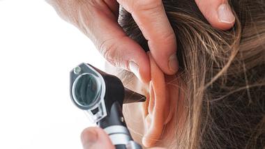 Das Ohr einer Frau wird mittels Ohrenspiegel untersucht. - Foto: KatarzynaBialasiewicz / iStock