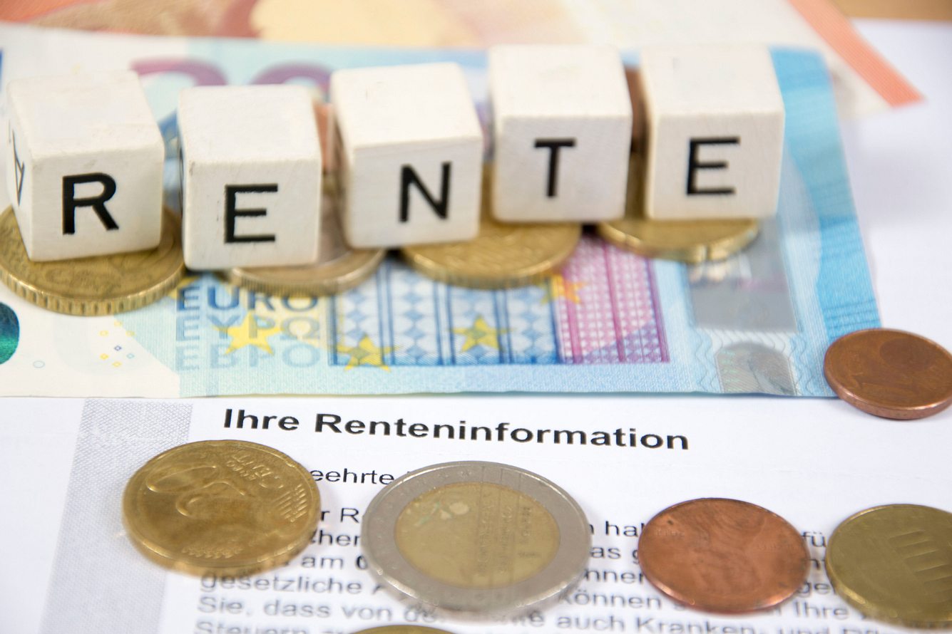 Fünf Würfel auf einem 20-Euro-Schein, die das Wort 'Rente' ergeben.