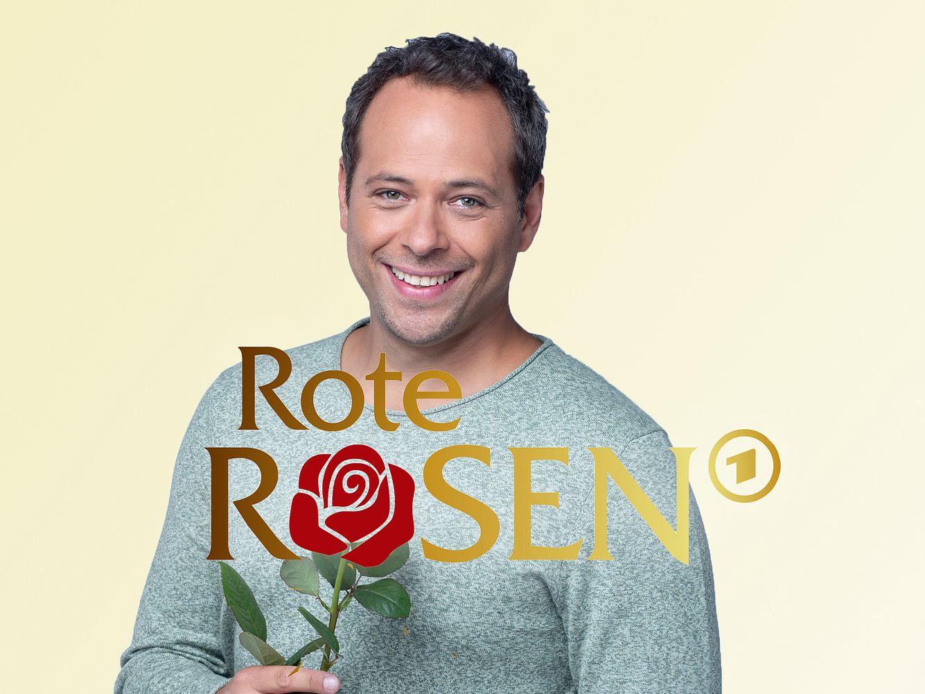 Daniel Hartwig als Leo vor einem schlichten Hintergrund mit 'Rote Rosen'-Logo