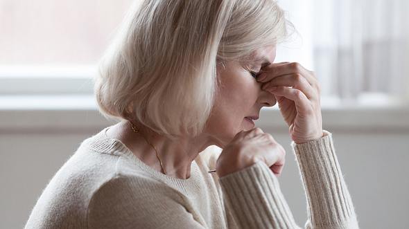 Eine Frau mittleren Alters leidet an Kopfschmerzen - Foto: fizkes / iStock