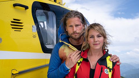 Sebastian Ströbel als Markus und Luise Bähr als Katharina vor dem Bergretter-Hubschrauber - Foto: ZDF/Stephanie Kulbach