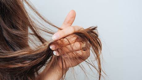 Frau hat trockenes Haar in der Hand - Foto: iStock/Cristalov
