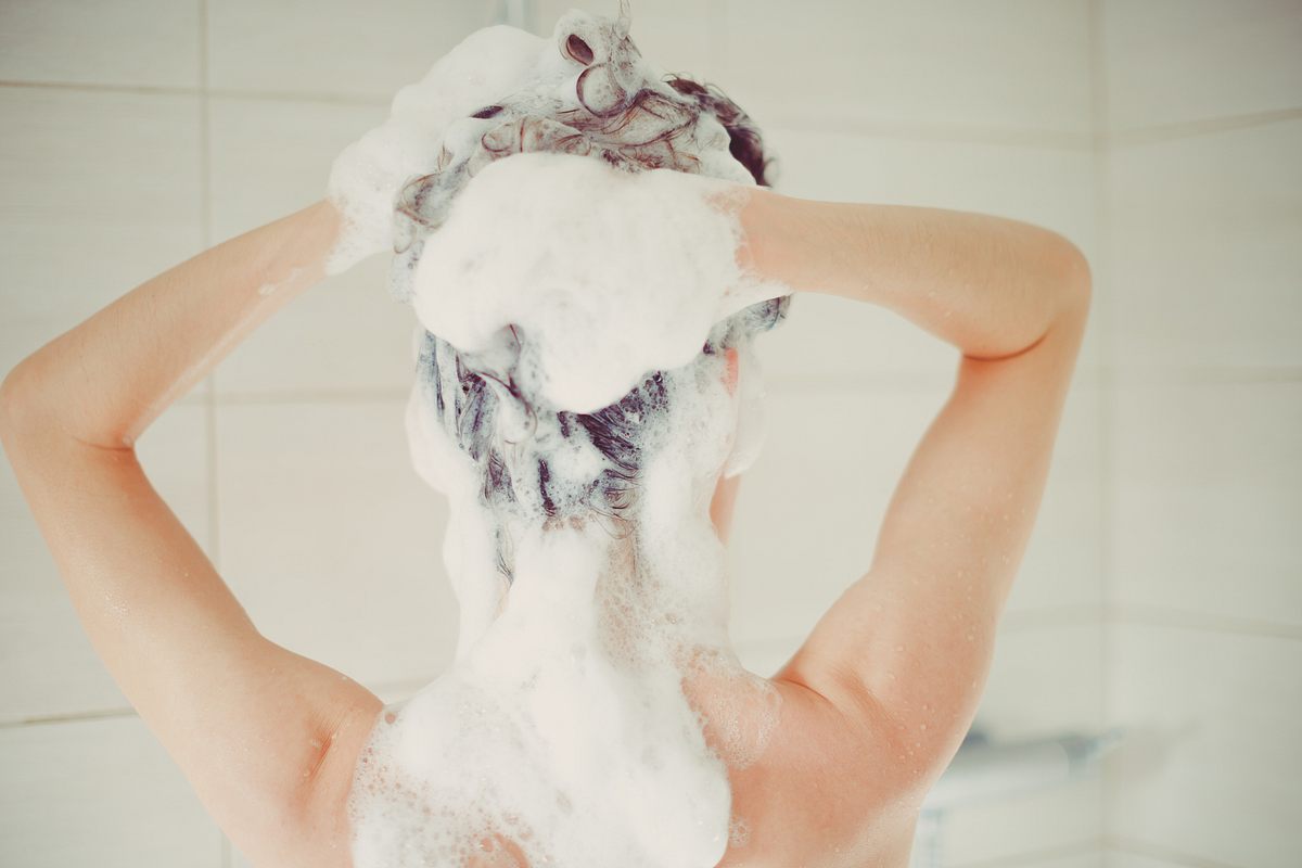 Frau wäscht sich die Haare mit einem Shampoo gegen Haarausfall