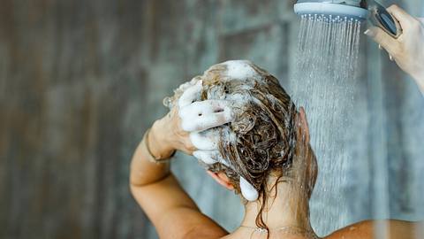 Frau wäscht sich die Haare mit Shampoo. - Foto: iStock/skynesher