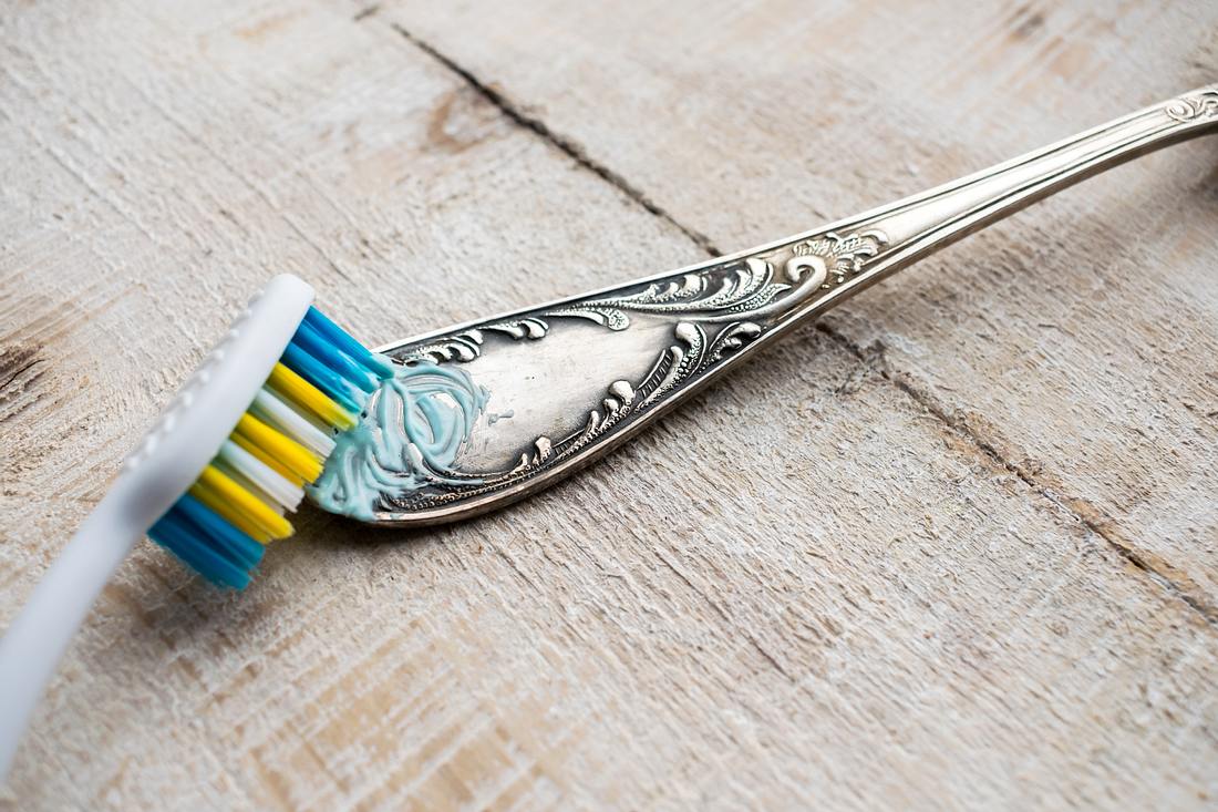Silberbesteck wird mit Zahnbürste gereinigt.