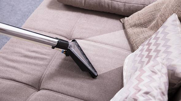 Person reinigt Sofa - Foto: iStock/AndreyPopov