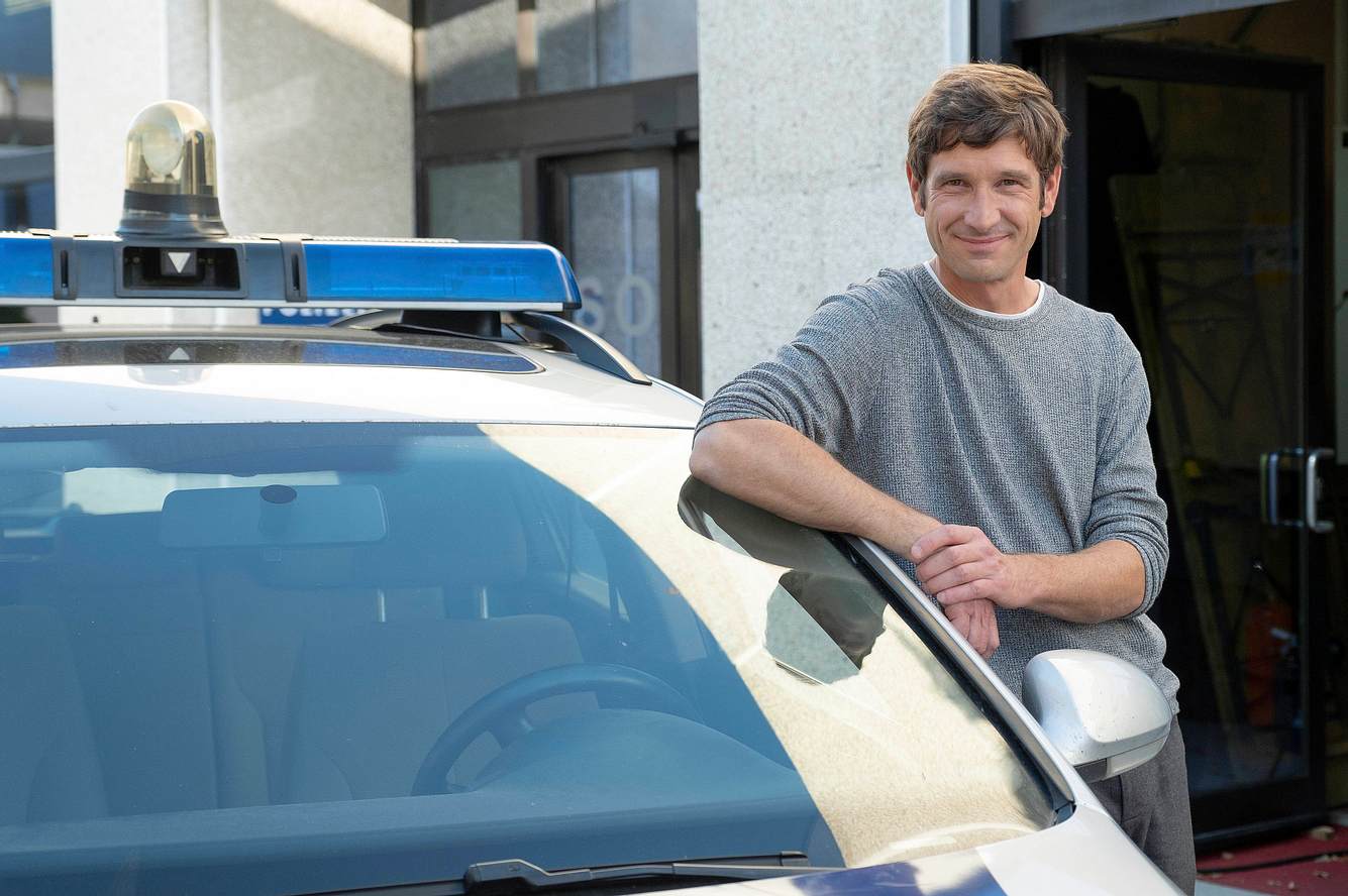 'SOKO'-Star Andreas Kiendl lehnt an einem Polizeiauto