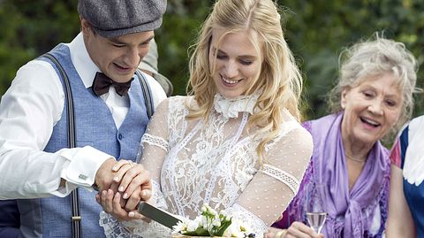 Viktor und Alicia von Sturm der Liebe schneiden ihre Hochzeitstorte an. - Foto: ARD / Stella Boda