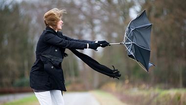 Eine Frau versucht ihren Regenschirm festzuhalten.  - Foto: iStock / RobertHoetink