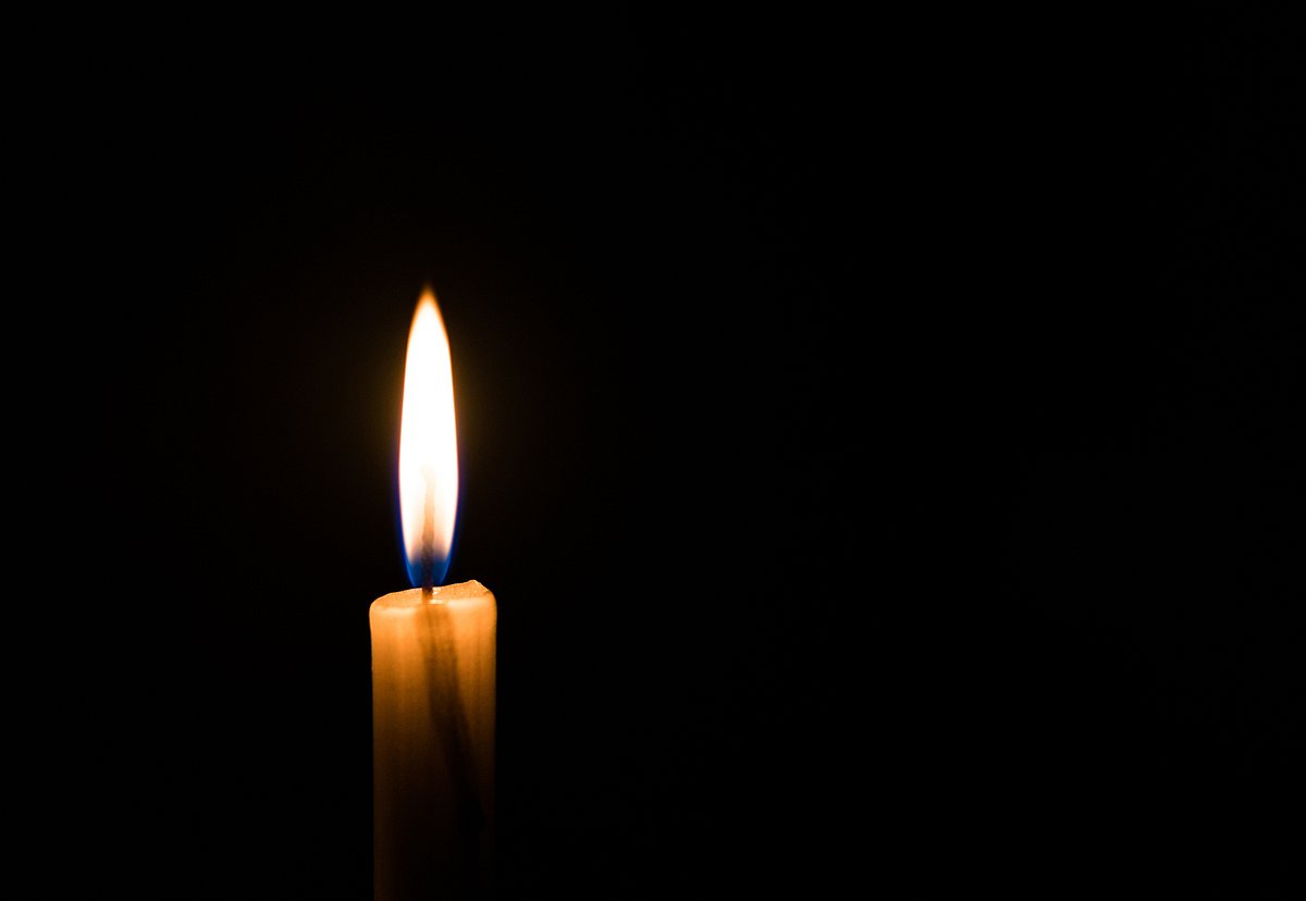 Eine brennende Kerze im Dunkeln. 