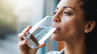 Frau trinkt ein Glas Wasser. - Foto: laflor / iStock