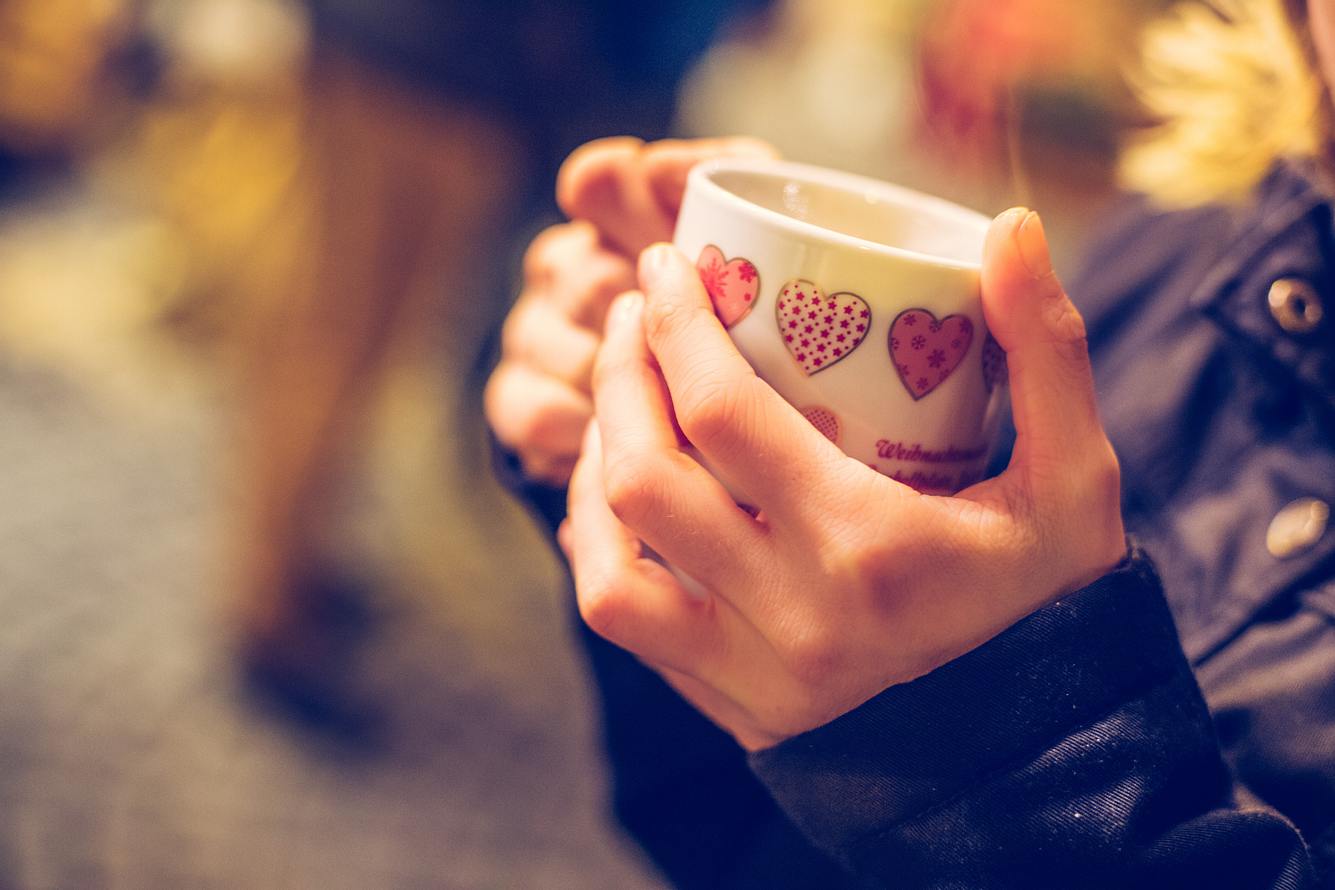 Frau hält eine Tasse mit Glühwein in den Händen. Frau hält eine Tasse mit Glühwein in den Händen.