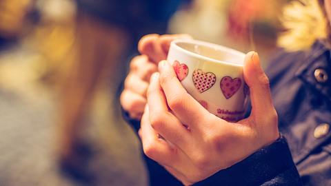 Frau hält eine Tasse mit Glühwein in den Händen.  - Foto: Patrick Daxenbichler / iStock